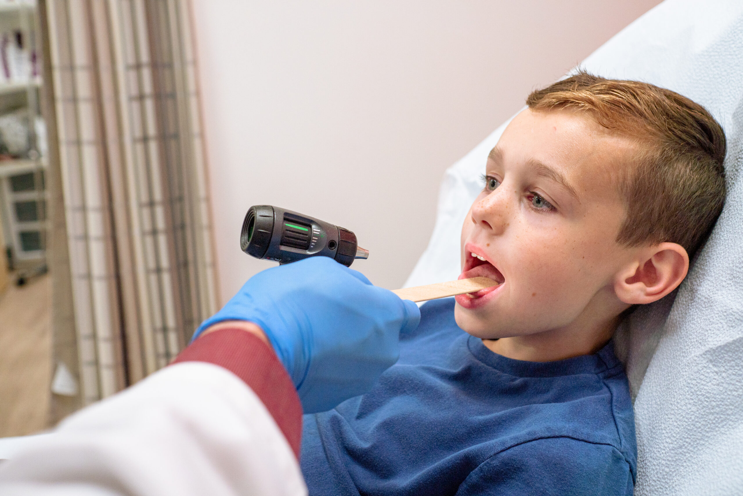 A medical professional examines a young boys throat.
